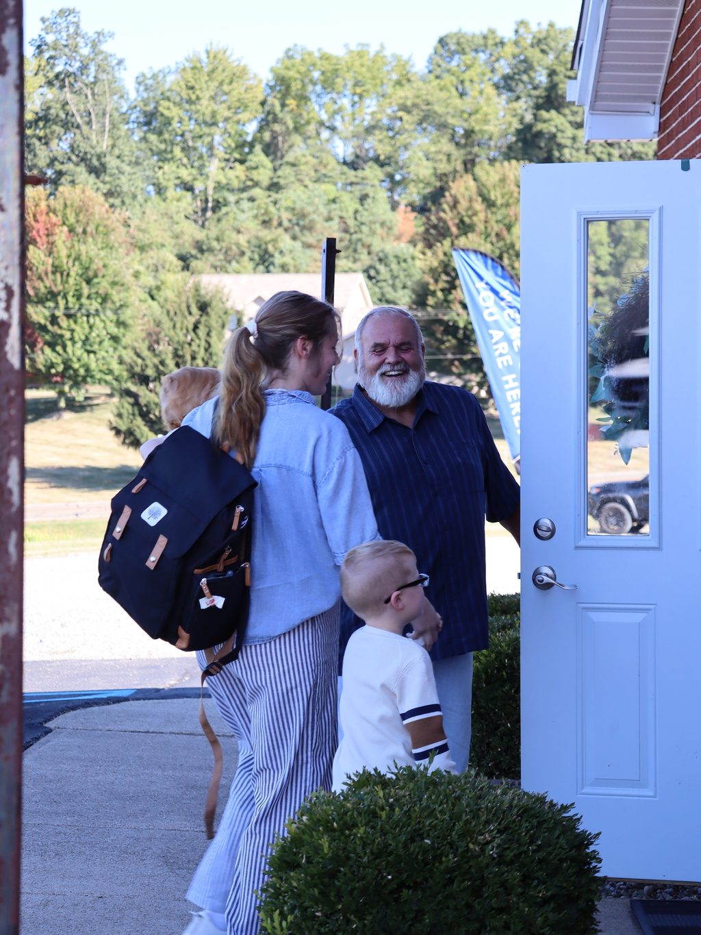A greeter welcoming a family at the door on a Sunday morning
